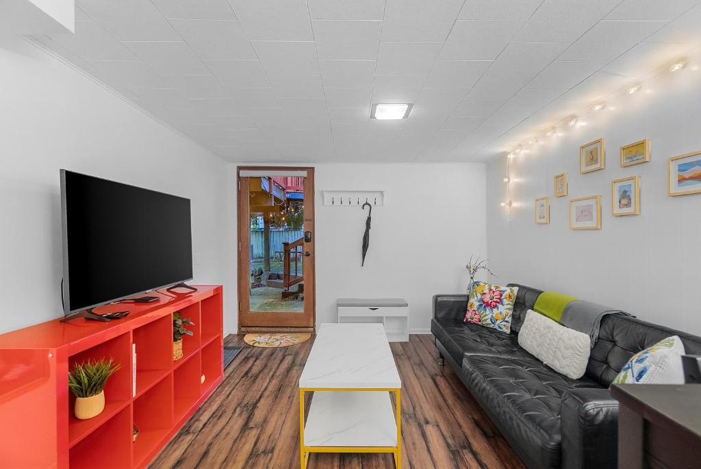 a living room with a black couch and a flat screen tv at Green Lake Zen Garden Basement in Seattle