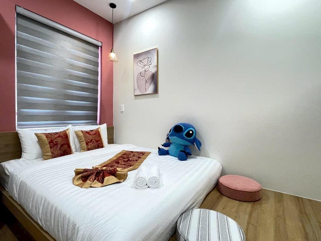 a bedroom with a bed with a blue stuffed animal on it at Villa IVY HOUSE in Bình Tú