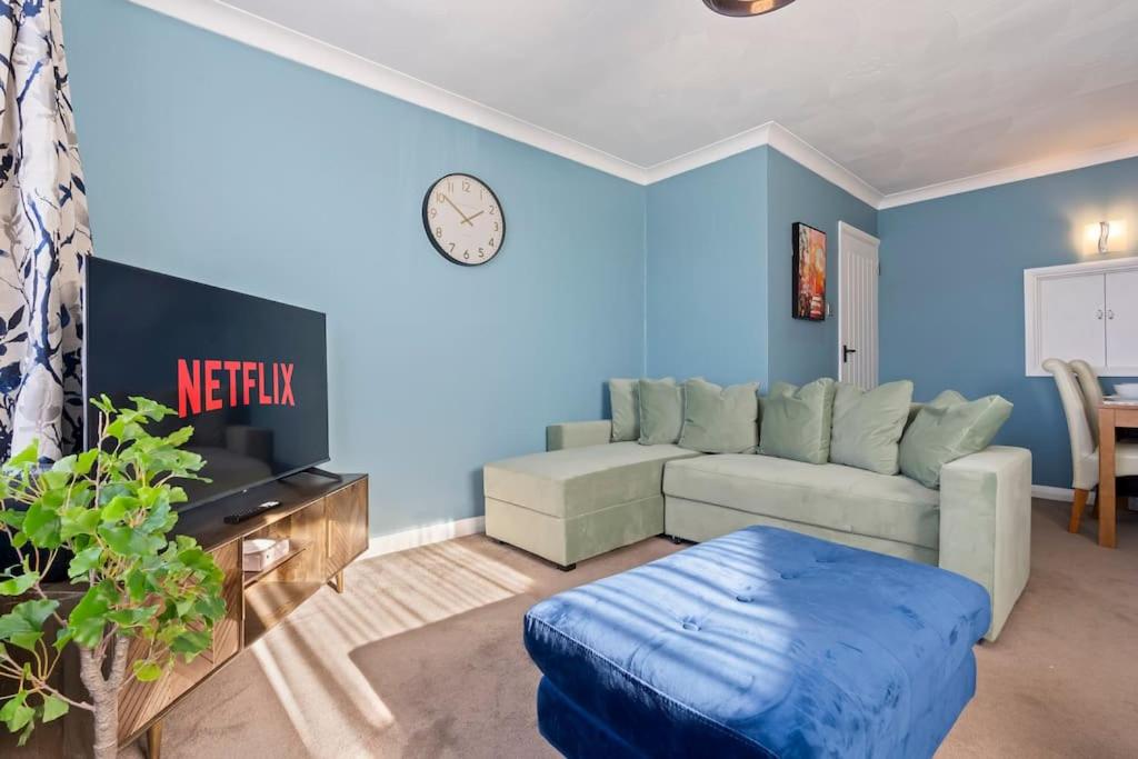 a living room with a couch and a clock on the wall at 3 bedroom Bungalow for Contractors,Workers,Relocation,Insurance,Family, Free Parking in Peacehaven