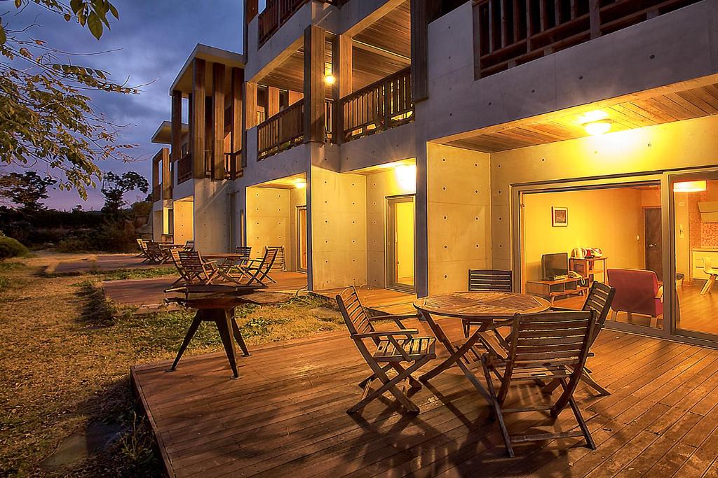 eine Terrasse mit einem Tisch und Stühlen sowie ein Gebäude in der Unterkunft Jeju Eco Suites in Seogwipo