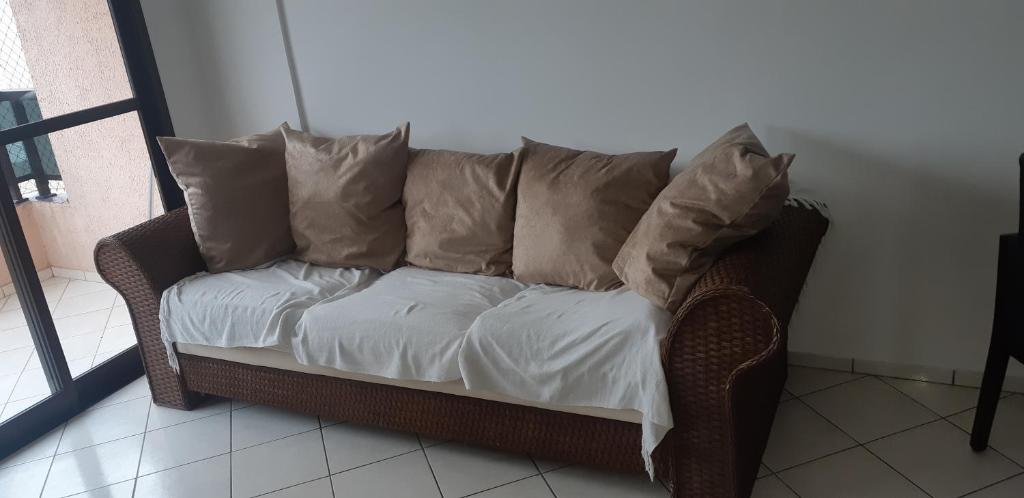 a couch with pillows sitting in a room at Apartamento a 50 metros da praia in Caraguatatuba