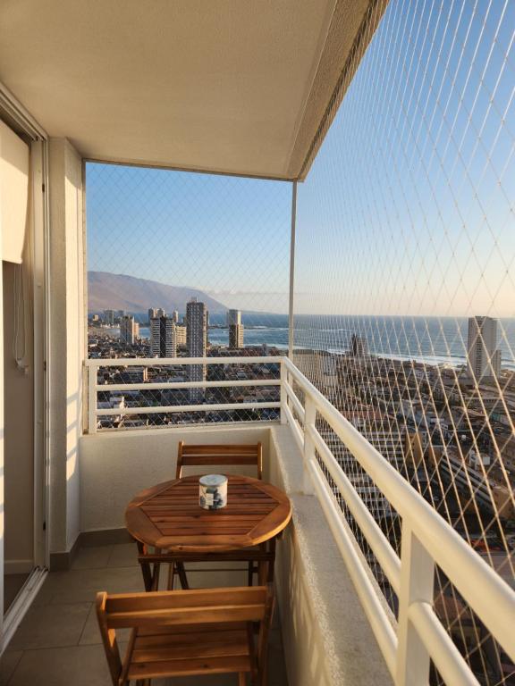 a balcony with a table and chairs and a view of the ocean at Departamento céntrico y cómodo in Iquique