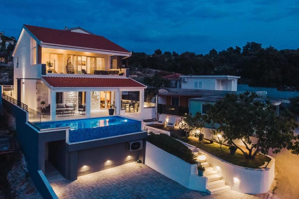 a villa with a swimming pool at night at Seaside luxury villa with a swimming pool Razanj, Rogoznica - 23572 in Rogoznica