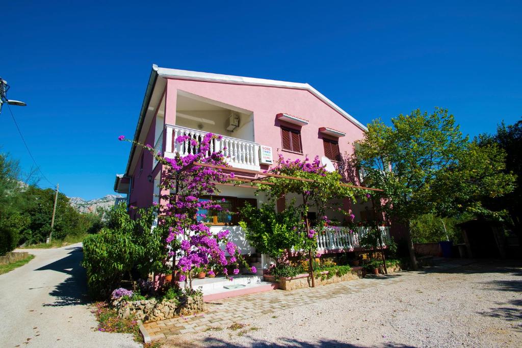 a pink house with flowers on the side of it at Apartments Žile in Starigrad