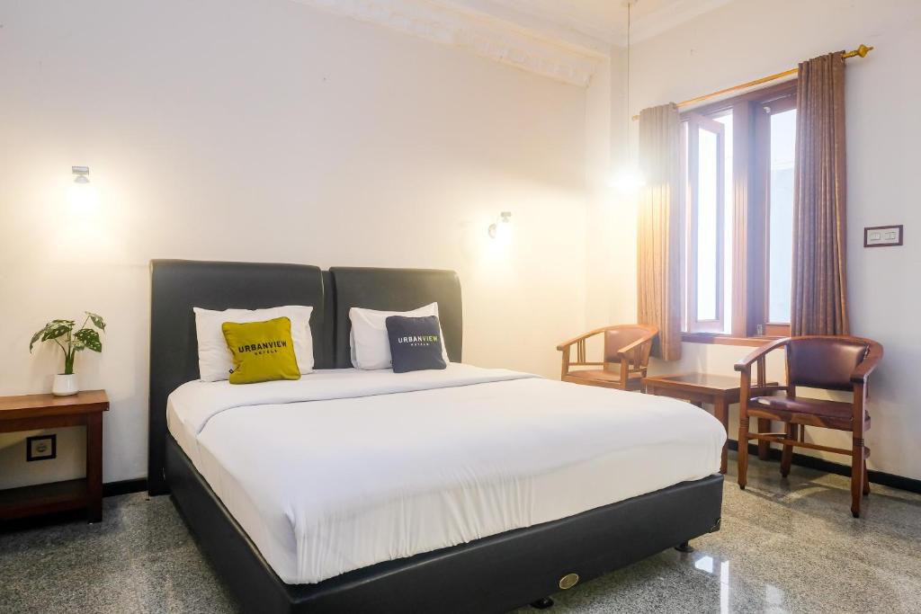 a bedroom with a bed with yellow pillows and a desk at Urbanview Omah Pari Boutique Hotel in Yogyakarta