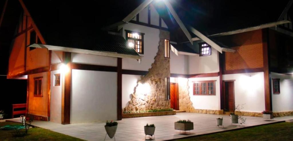 a house with a courtyard with potted plants in front of it at Recanto Lucerna in Campos do Jordão