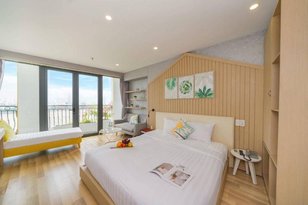 a bedroom with a large white bed and a balcony at Happy Day Riverside Hotel & Spa Danang by Haviland in Danang