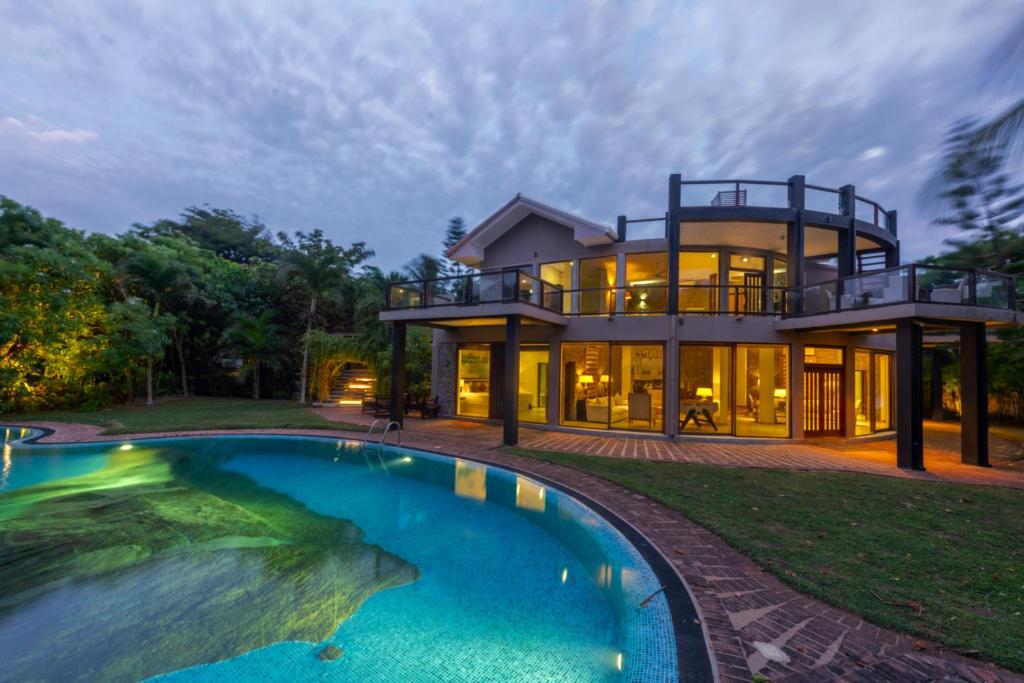 a large house with a swimming pool in front of it at Villa Thuya - 3 Bedroom Oceanfront Villa with Pool in Balapitiya