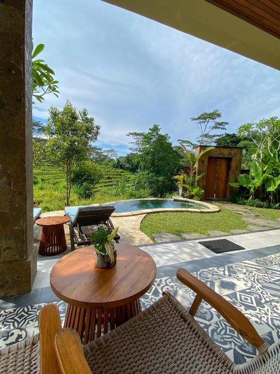 a patio with a table and chairs and a pool at Abian Ayu Villa in Sidemen