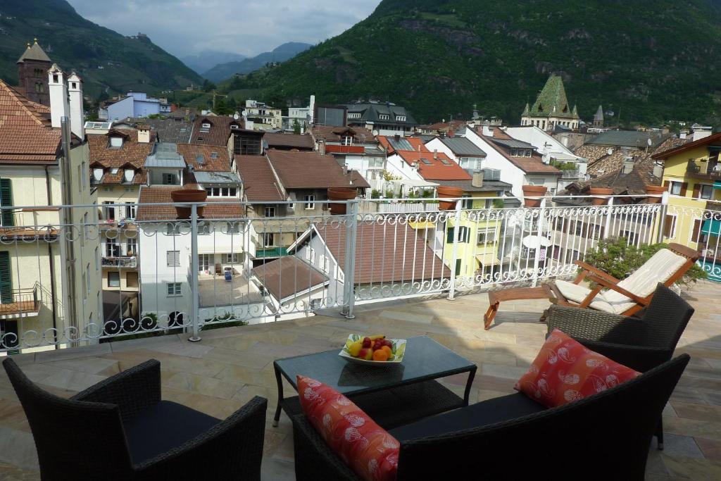 a balcony with chairs and a table and a city at Apartment Leonardo in Bolzano