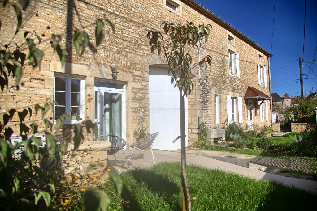 a brick house with a white door and a chair at Gîte - Le Saule Rêveur in Nantilly