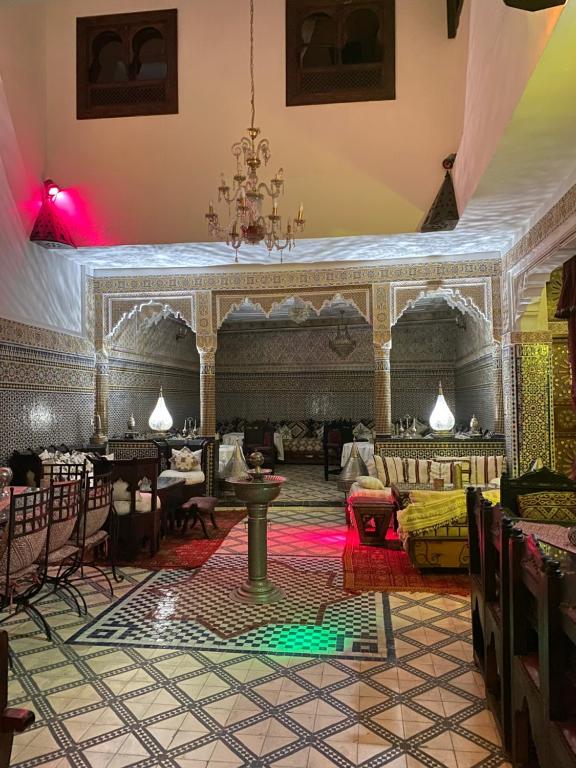 una habitación con un escenario, mesas y sillas en Riad Lahboul, en Meknès