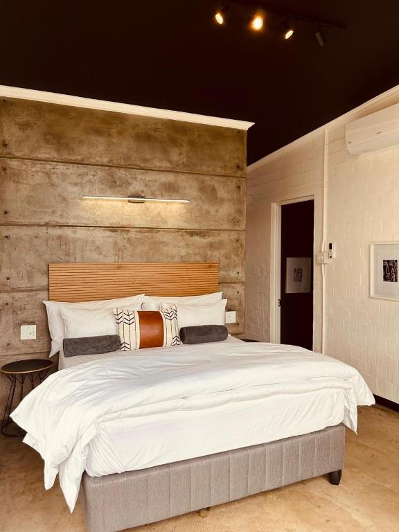 a bedroom with a large white bed with a wooden headboard at Cellar Pods Red in Robertson