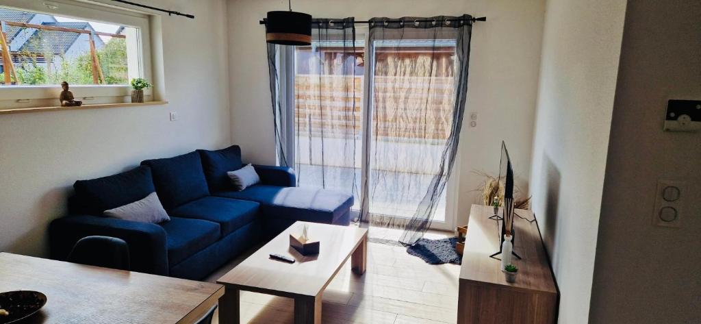un salon avec un canapé bleu et une table dans l'établissement Gite Alsacien, à Roggenhouse
