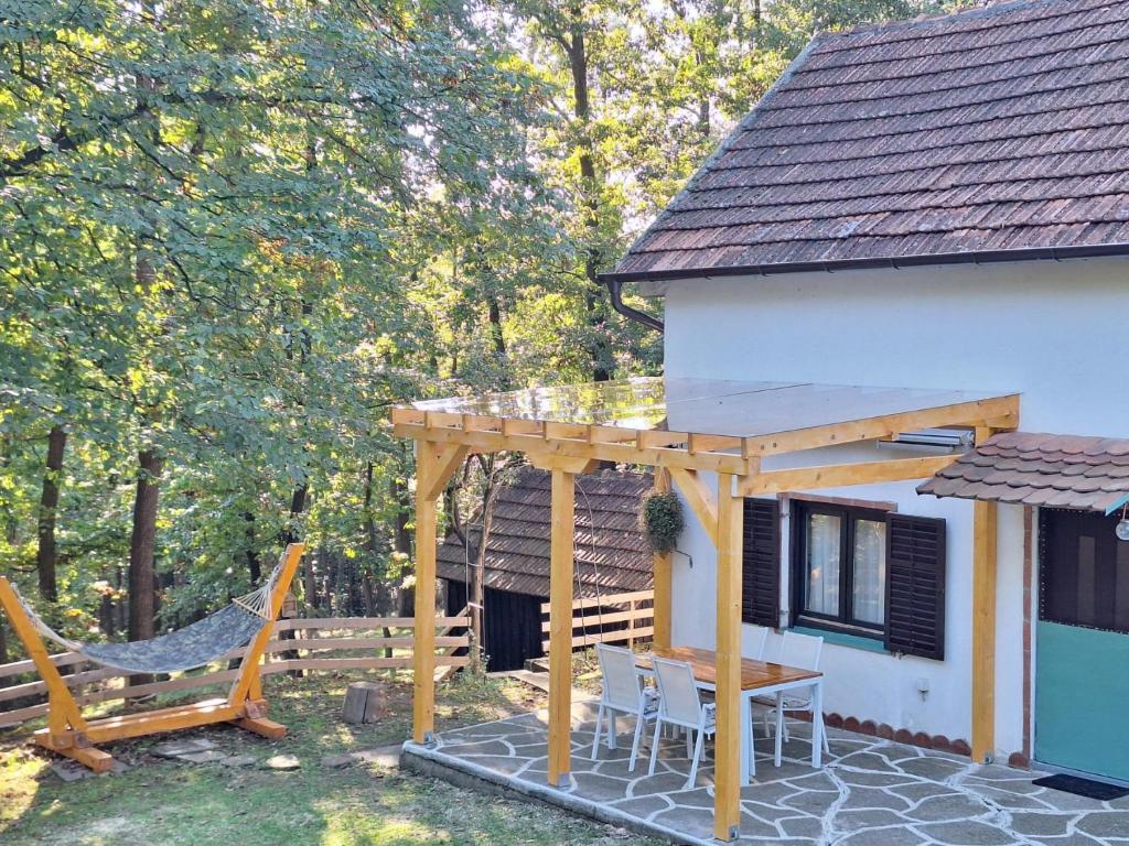 a patio with a wooden pergola next to a house at Vikendica WoodNook Kosmaj - Šumski kutak in Sopot