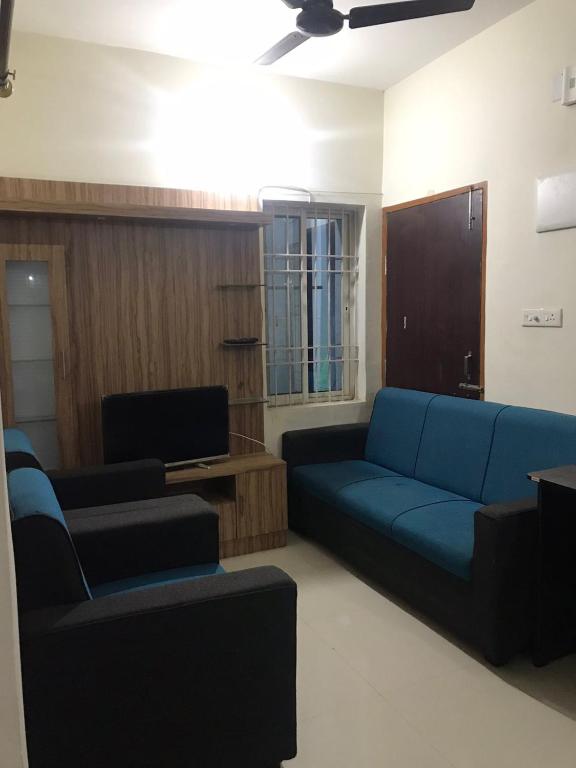 ブバネーシュワルにあるDDM Avenueの青いソファと椅子のあるリビングルーム