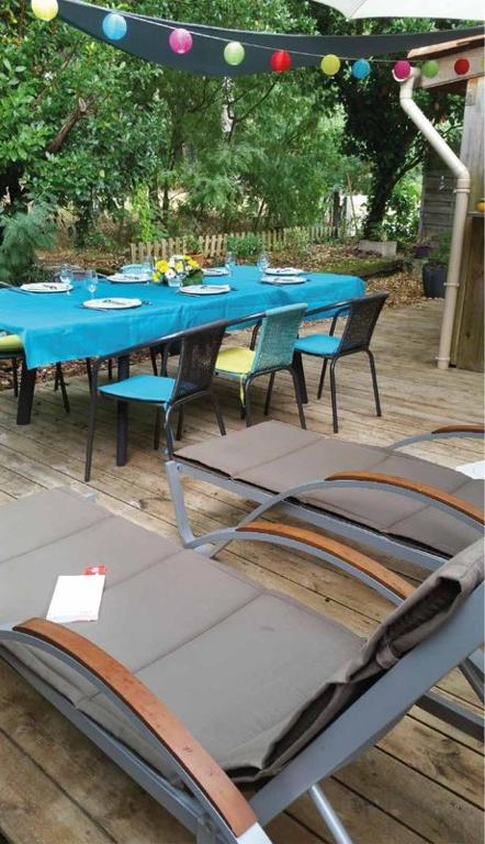 une table bleue et des chaises assises sous un parasol dans l'établissement Détente et Nature Maisonnette Conviviale pour 6 Personnes dans un Village de vacances, à Gujan-Mestras