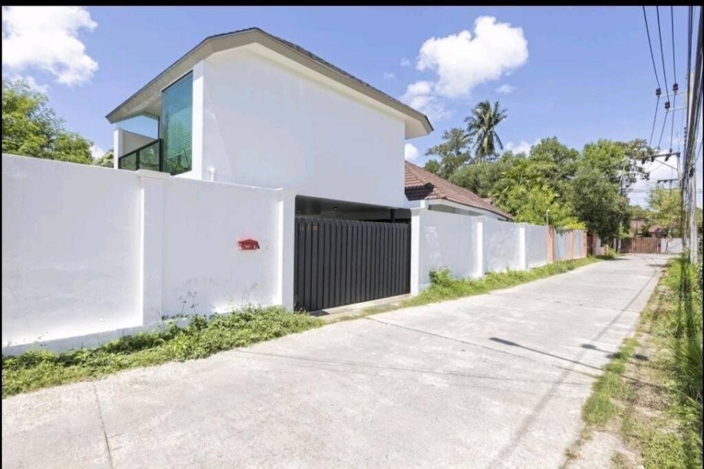 a white house with a fence on a street at Happy Villa in Choengtalay in Laguna Phuket