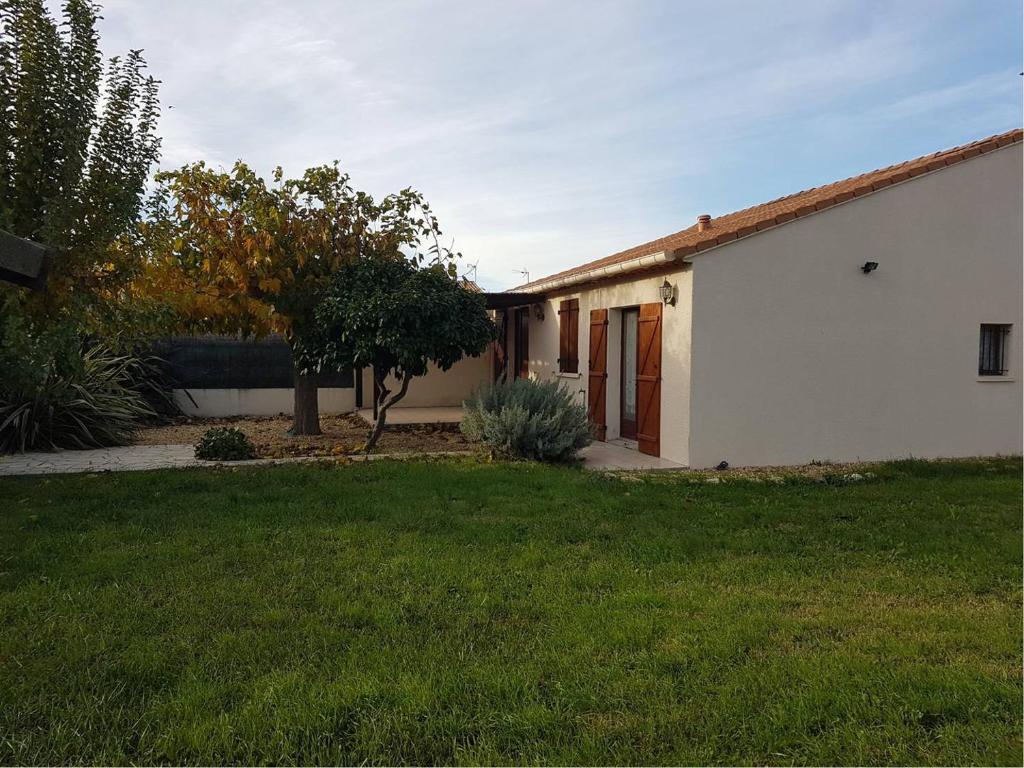 une maison avec une cour d'herbe devant elle dans l'établissement Superbe villa de plain pied avec grand jardin - 6RADI8, à Saint Cyprien Plage