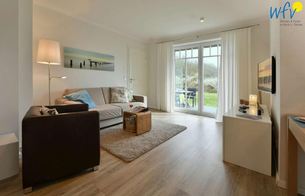 a living room with a couch and a table at Bootshaus in den Duenen - 5 - "Ferienwohnung Duenengefluester" in Wangerooge