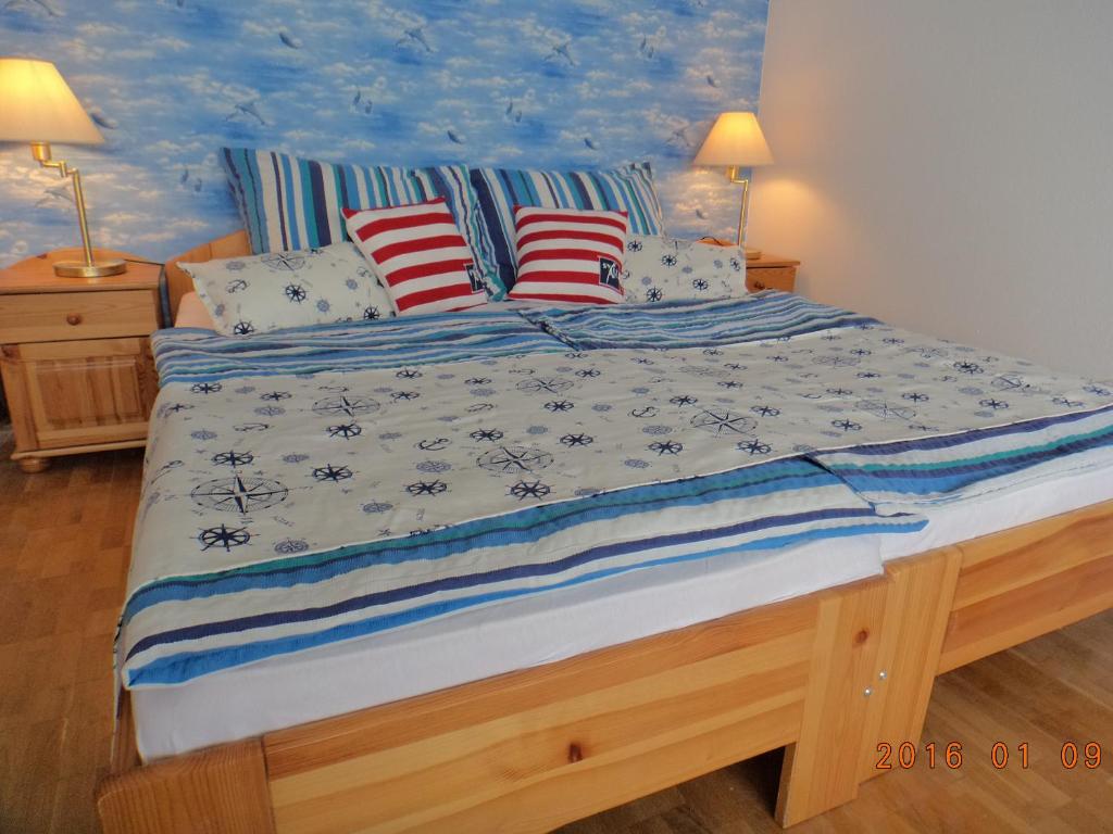 a bed with blue and white sheets and pillows at Boathouse Balatonlelle with Sauna & Salty Bath Tub in Balatonlelle