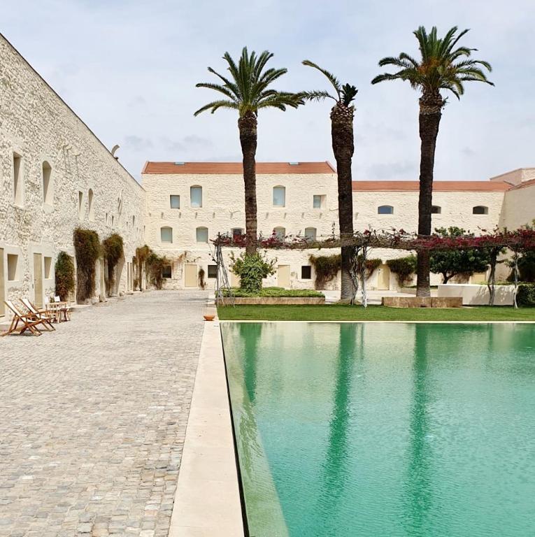 a courtyard with palm trees and a swimming pool at Apartamento Convento das Bernadas Tavira in Tavira