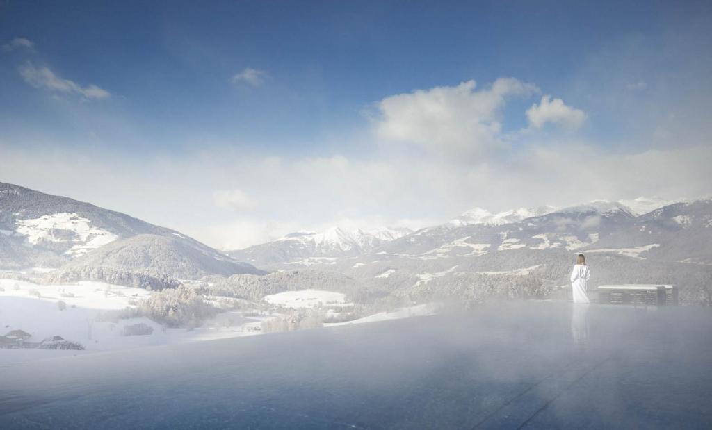 Un homme debout au sommet d'une montagne dans la neige dans l'établissement Hotel Winkler Sport & Spa Resort, à San Lorenzo di Sebato