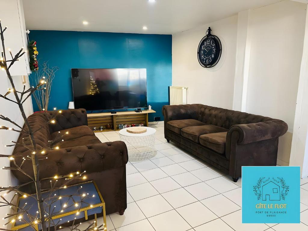 a living room with two couches and a flat screen tv at Gîte Le Flot in Saint-Florentin
