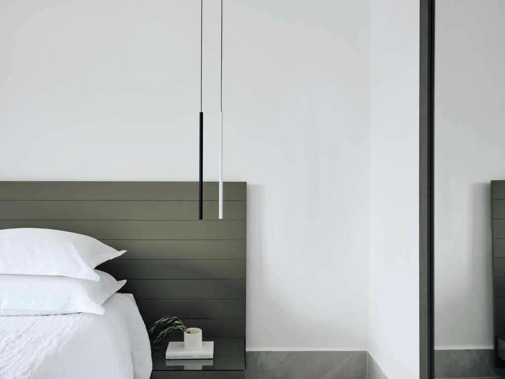 a bedroom with a white bed and a green wall at Acteon Hotel in Ios Chora