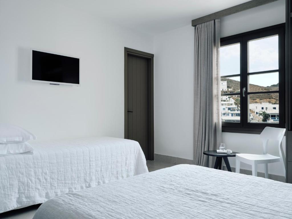 a white hotel room with two beds and a window at Acteon Hotel in Ios Chora