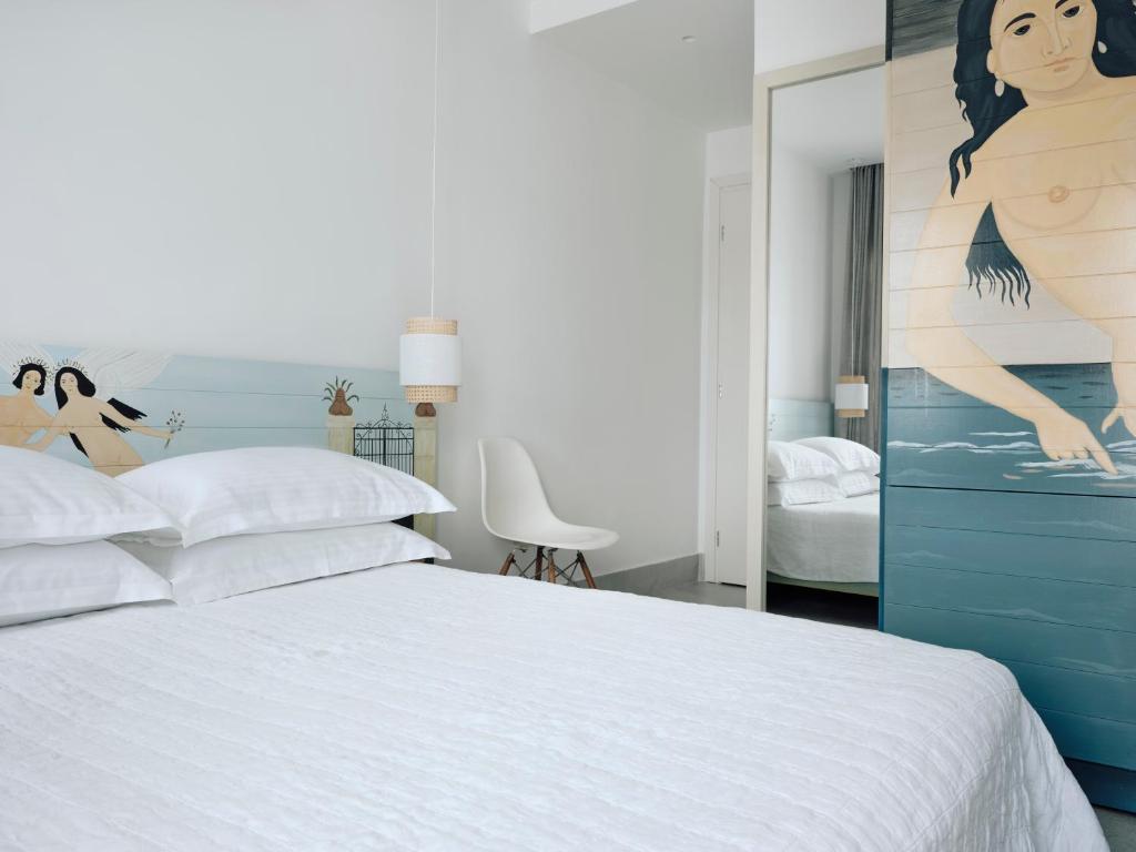 a bedroom with a bed and a painting of a woman at Acteon Hotel in Ios Chora