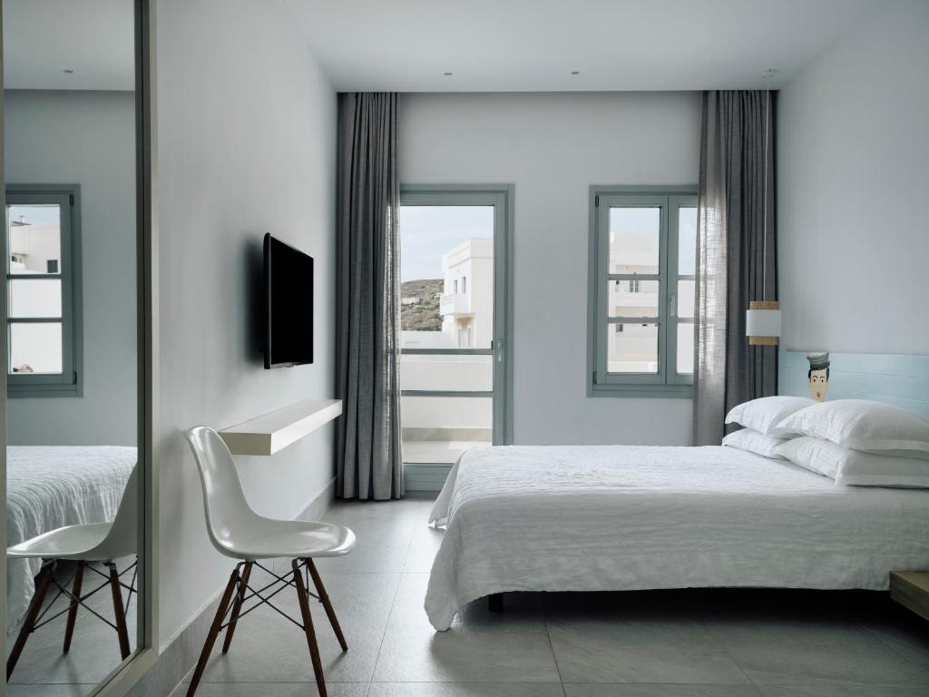a bedroom with a white bed and a chair at Acteon Hotel in Ios Chora