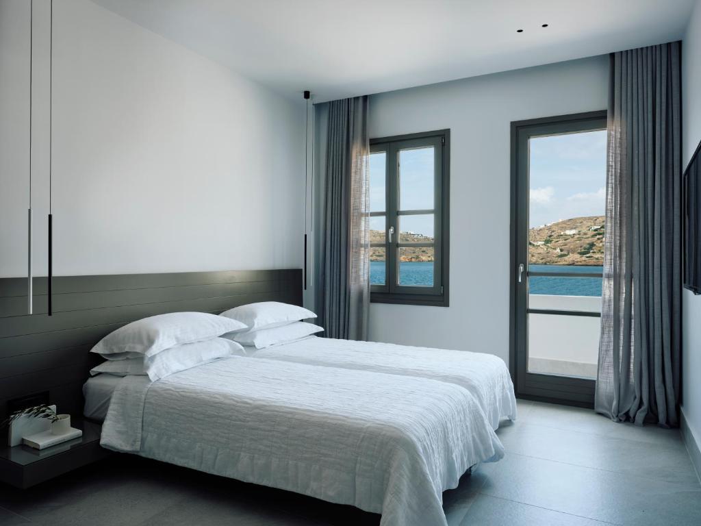 a bedroom with a bed with a view of the ocean at Acteon Hotel in Ios Chora