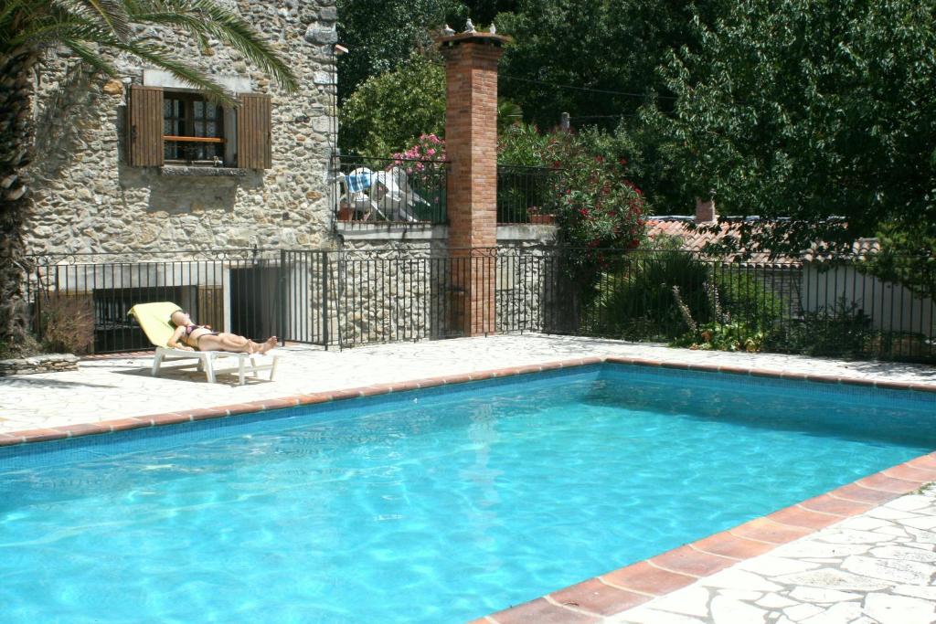 a person sitting in a chair next to a swimming pool at La Maison de Yana in Saint-Marcel-dʼArdèche