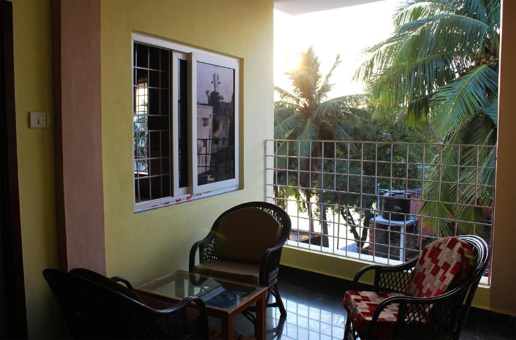 un balcone con 2 sedie, un tavolo e una finestra di Vinodhara Guest House a Mamallapuram