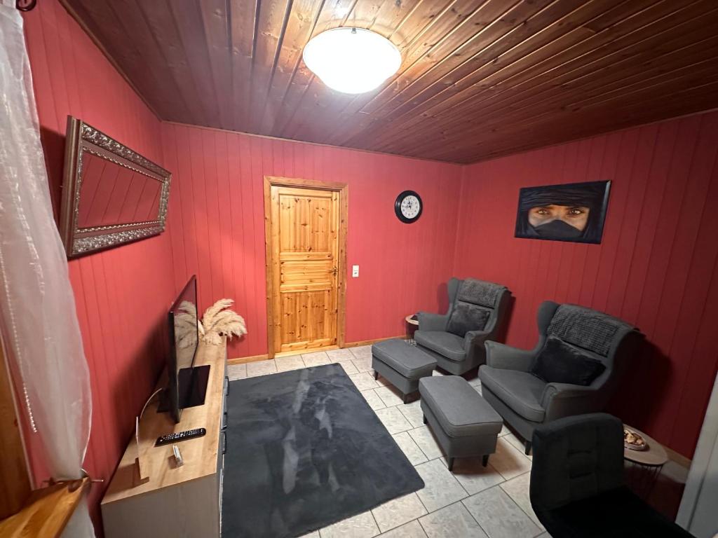 una sala de estar con paredes y sillas rojas y una puerta. en Apartment Holzhaus, en Cuxhaven