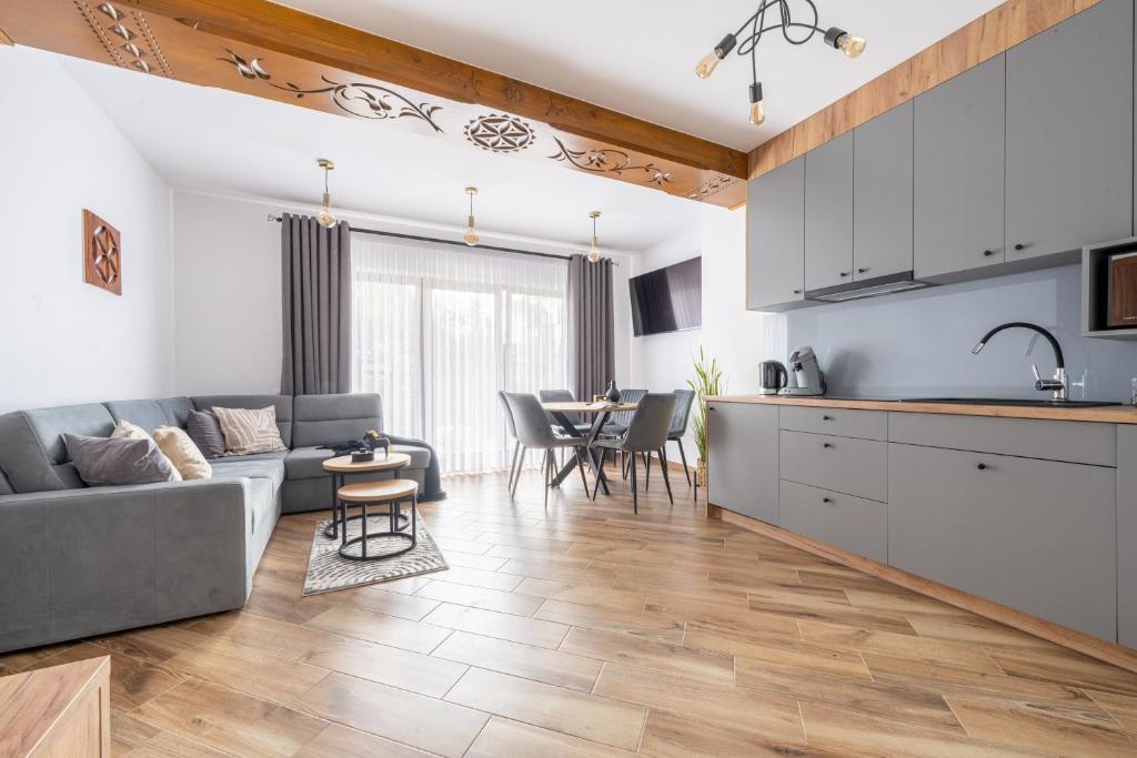 a kitchen and living room with a couch and a table at Para Apartments - Dwupoziomowe Apartamenty in Biały Dunajec