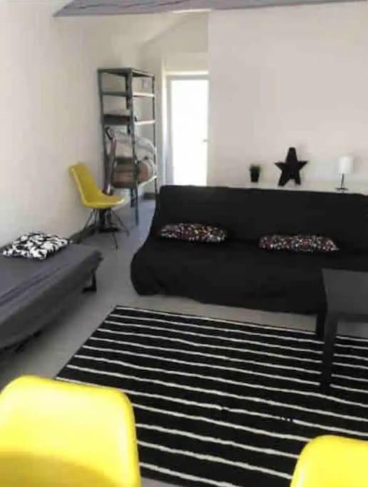 - un salon avec un lit noir et une chaise jaune dans l'établissement Studio design proche Colmar, à Sainte-Croix-en-Plaine