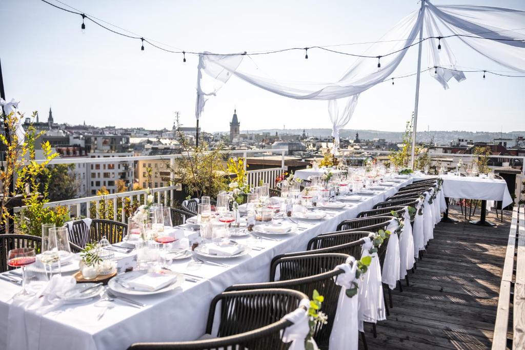 a long table with white tables and chairs on a roof at Pytloun Boutique Hotel Prague in Prague