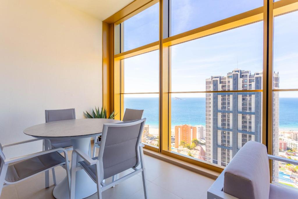 Un comedor con mesa y sillas y grandes ventanales. en Intempo by Holuxe - 131 - 13th floor, en Benidorm