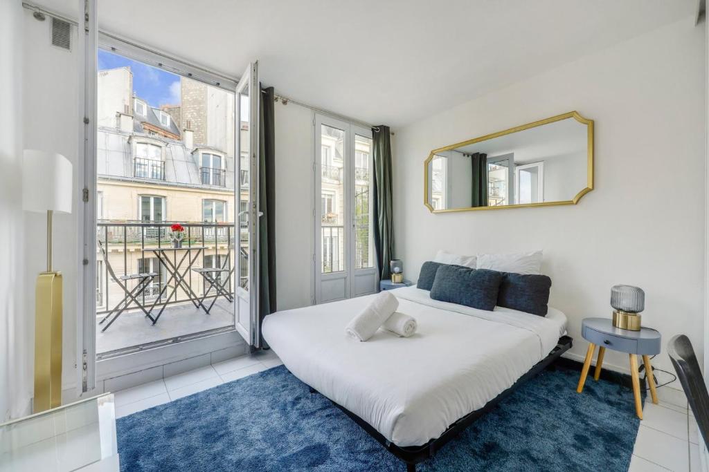 une chambre avec un lit et une grande fenêtre dans l'établissement Moulin Rouge Terrasse, à Paris