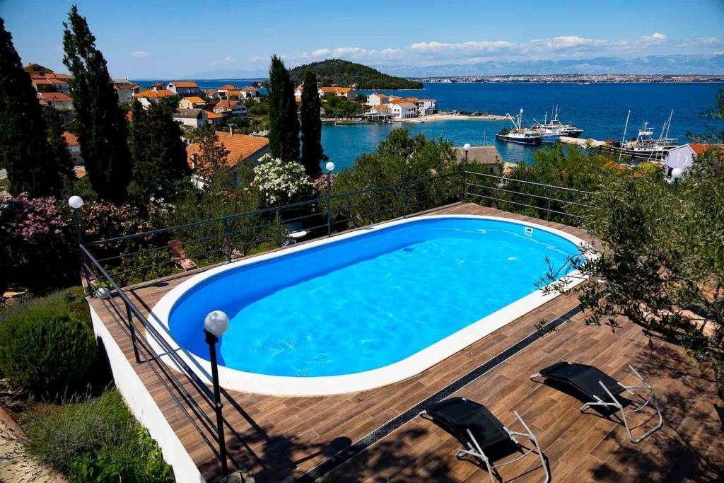 een zwembad met stoelen en uitzicht op het water bij Apartments Novis in Kali