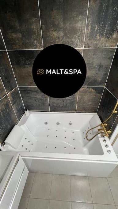 un panneau noir sur le mur au-dessus d'une baignoire blanche dans l'établissement Malt&SPA jacuzzi privatif, à LʼIsle-dʼAbeau