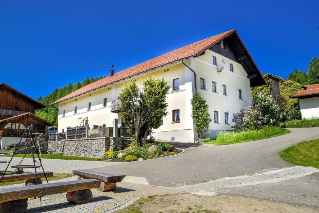 een groot wit gebouw met een bank ervoor bij Urlaub auf dem Haberlhof in Lohberg