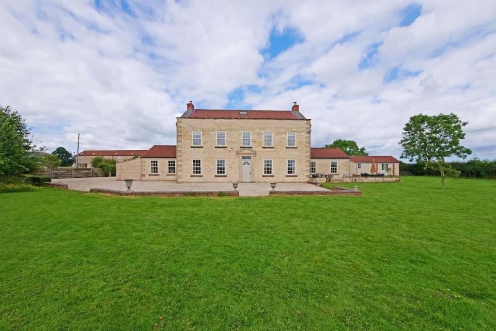 a large building with a grass field in front of it at Salton Retreat in Great Edston