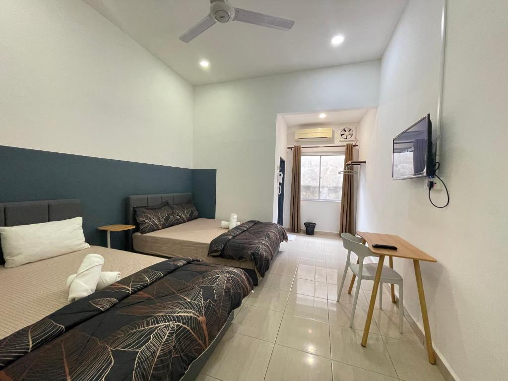 安顺Cozy Roomstay Teluk Intan的一间卧室配有两张床、一张桌子和一台电视。