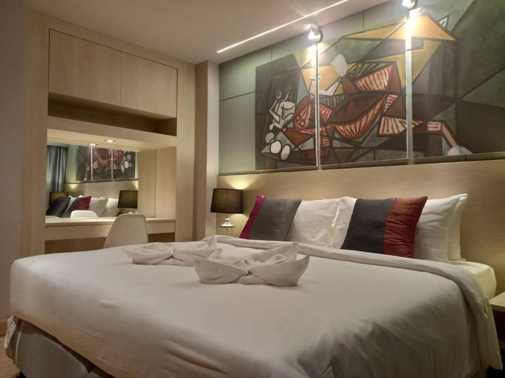 a bedroom with a large white bed with a painting on the wall at AD resort ชะอำ in Ban Bo Khaem