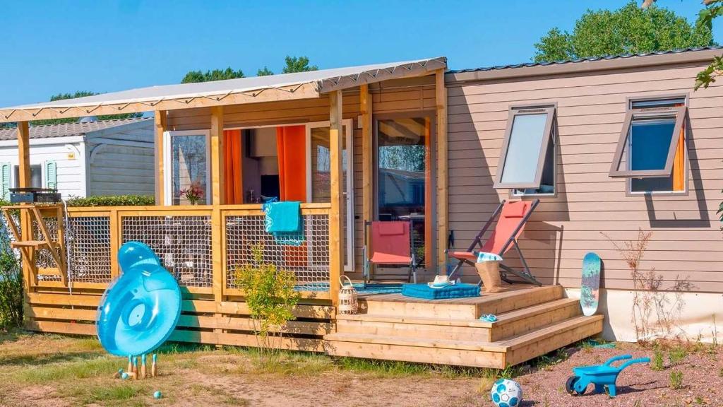 ein kleines Haus mit einer Veranda und einer Terrasse in der Unterkunft Camping 4 étoiles - Parc aquatique - eeic0a in La Tranche-sur-Mer