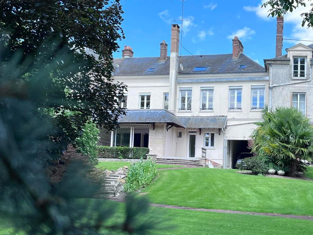 une grande maison blanche avec une cour verdoyante dans l'établissement La Maison de Colette, à Trie-Château