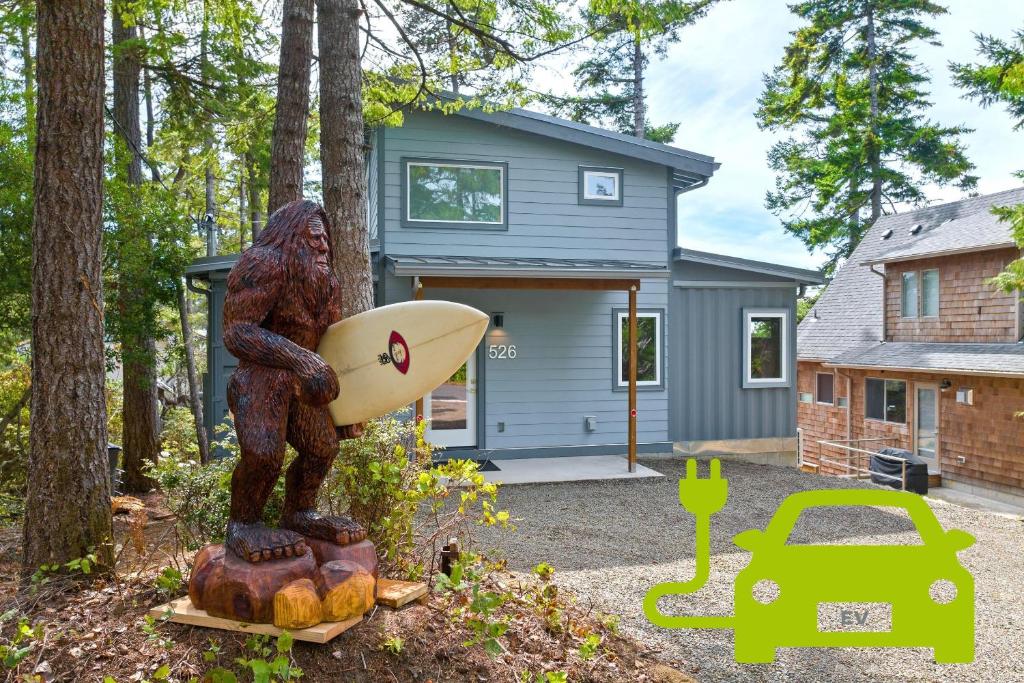 a statue of a man holding a surfboard in front of a house at Sasquatch House MCA#50631 in Manzanita